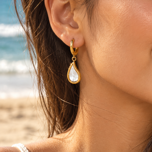 Mother of Pearl Teardrop gold-tone earrings worn on a beach