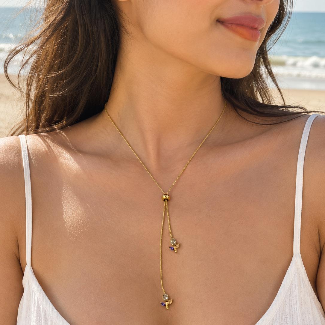 Gold-tone lariat necklace with colorful floral crystal drops worn on a beach