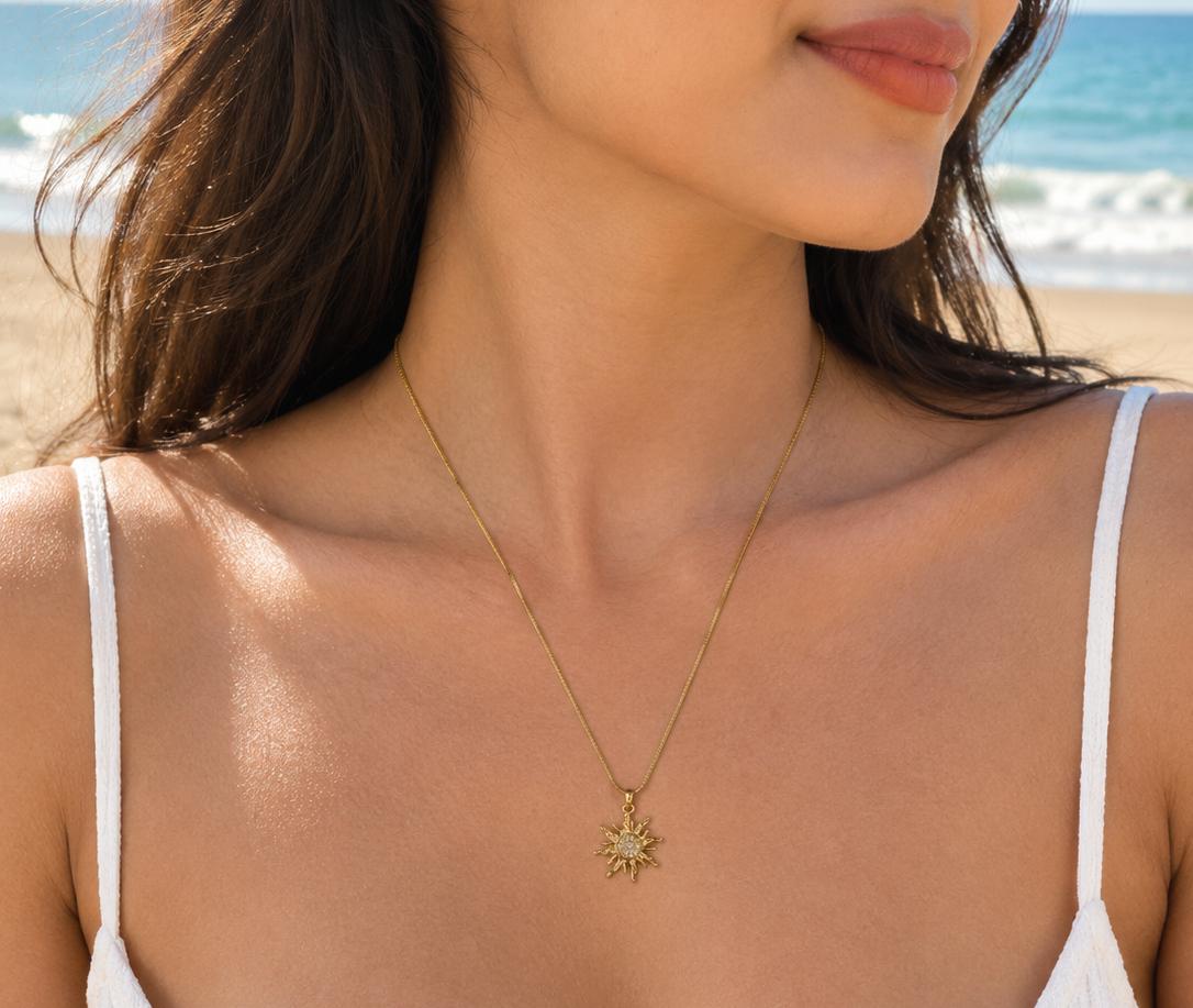 Gold-tone sunburst pendant necklace worn on a beach