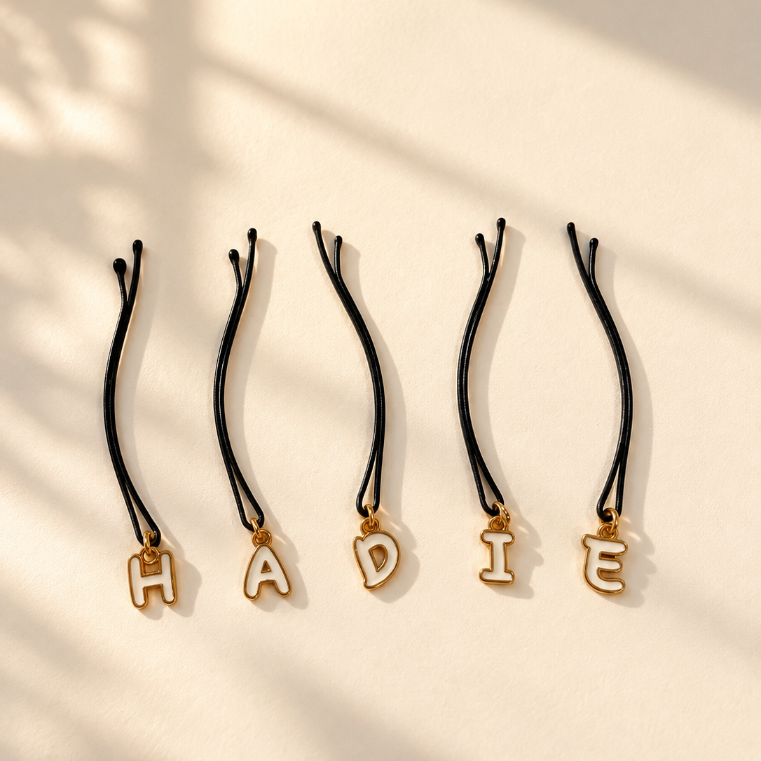 Five gold outline letter hair pins spelling HADIE