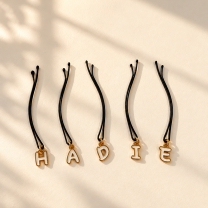 Five gold outline letter hair pins spelling HADIE