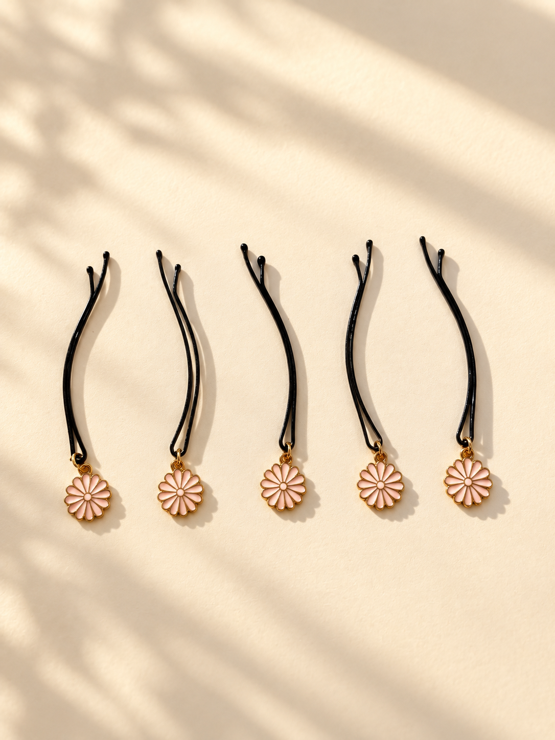 Five pink daisy charm hair pins displayed individually