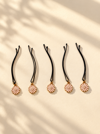 Five pink daisy charm hair pins displayed individually