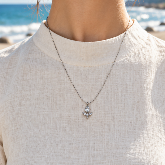 Silver-tone necklace with crystal leaf pendant worn at the beach